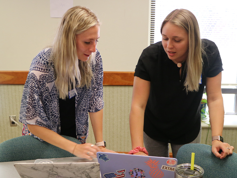 Two students collaborating on a project with their laptops