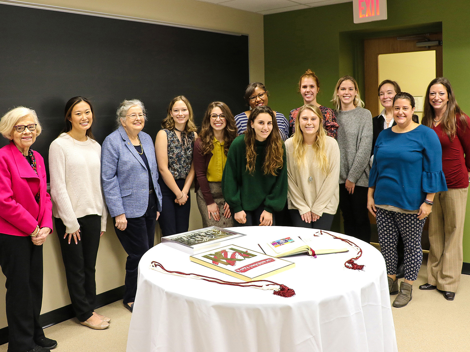 Kappa Omicron Nu members pose around a table after a meeting.