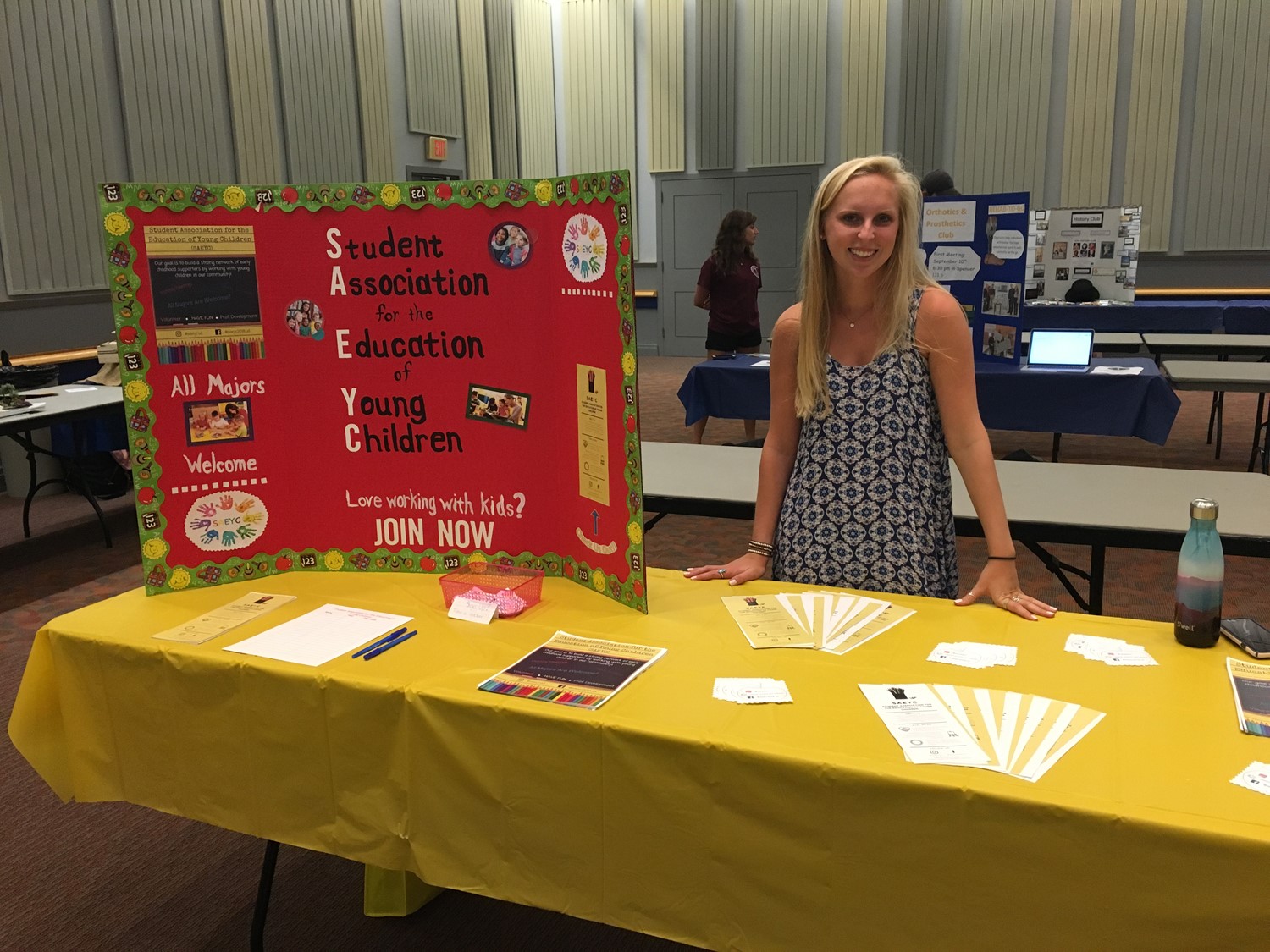 Member fo Student Association for the Education of Young Children stands behind an information table.