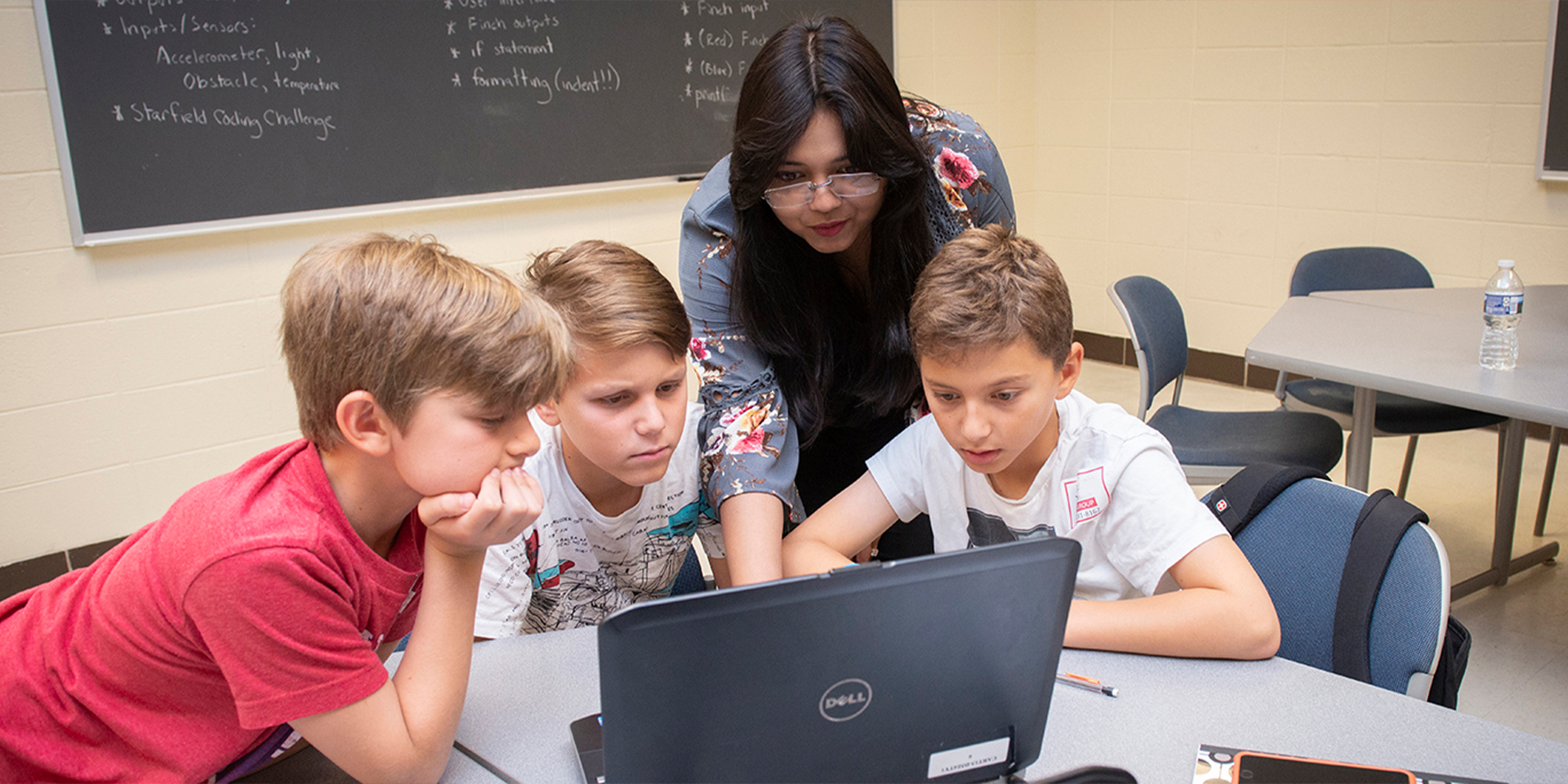 Teacher helping students with computer assignment