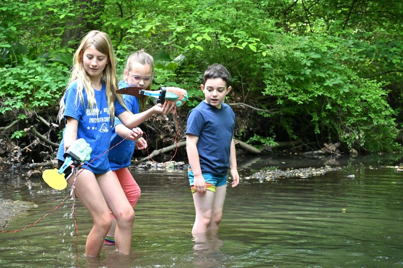 Elementary students test their aquatic robots in the creek behind University of Delaware’s The College School.
